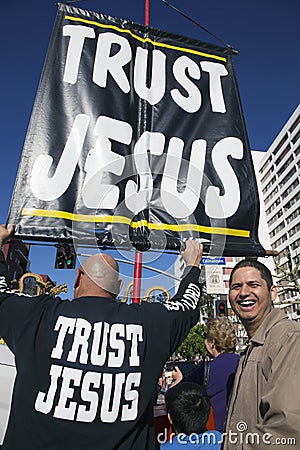 Sign reads Trust Jesus sign and man mocking him, Chinese New Year, Los Angeles, California, USA Editorial Stock Photo