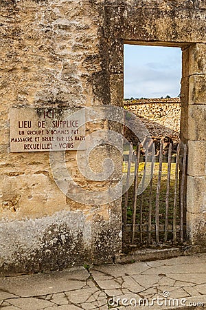 Sign saying `Place of Torture, a group of men was massacred and burnt by the Nazis` in the martyr village of Oradour-sur-Glane Editorial Stock Photo
