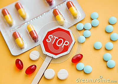 Sign Stop drugs. Colorful pile of medicines and painkillers on yellow background Stock Photo