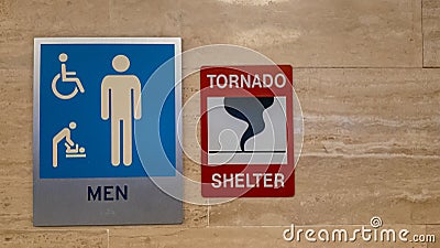 Sign of a tornado shelter next to a sign of a men`s restroom Stock Photo