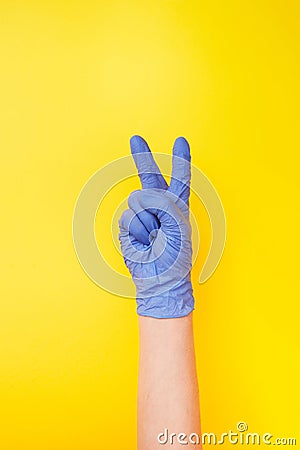 Sign victory made female`s hand in rubber protective glove. Stock Photo