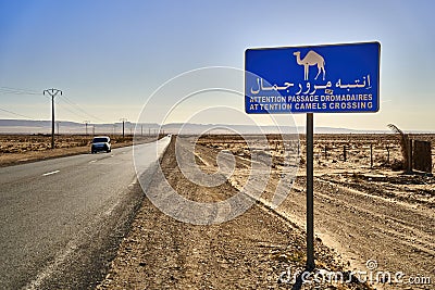 Sign warning of camels crossing the road at the edge of the gravel track through the desert of southern Tunisia Editorial Stock Photo