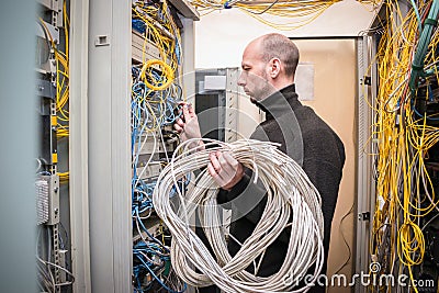 The signalman holds in his hands many wires wound in a ring. The specialist works in the server room of the data center. A man swi Stock Photo