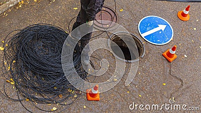 Signalman worker pulling an electric cable through the city well Stock Photo