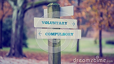 Signpost with arrows pointing two opposite directions towards Voluntary and Compulsory Stock Photo
