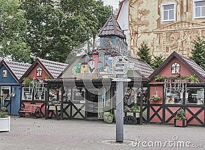 Signpost with arrows and wooden colorful small houses with Baltic souvenirs in tourist area. Editorial Stock Photo