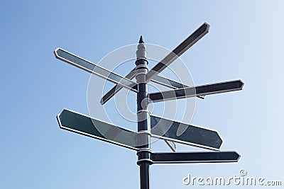 Signpost Pointing In Many Directions Against Blue Sky Stock Photo