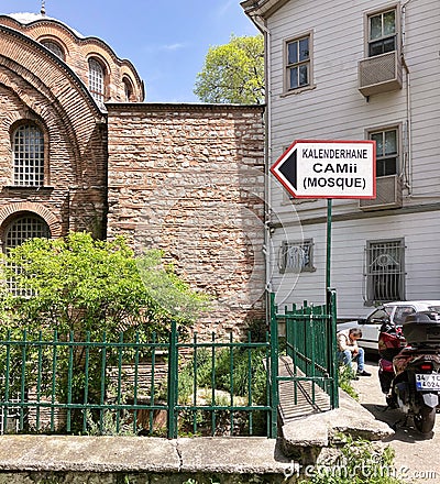 Signpost pointing to the Eski Imaret Mosque, a historic mosque in Istanbul, Turkey, with part of the mosques facade Editorial Stock Photo