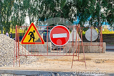 signs entry is prohibited and roadworks are underway behind which there is pile of rubble and protective concrete blocks Stock Photo