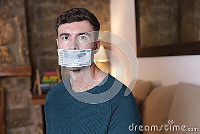Silenced man with money covering mouth Stock Photo