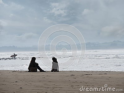 Silhoettes of mother, daughter and a serfer on a beach. Calm, peacefull atmosphere. Silverstrand, Sligo Ireland Stock Photo