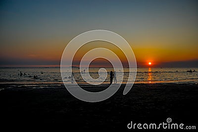 Silhouete people sunset on the beach. Stock Photo