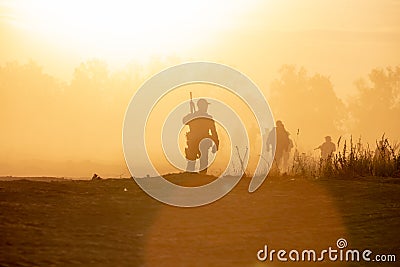 Silhouette action soldiers walking hold weapons the background is smoke and sunset and white balance ship effect dark Editorial Stock Photo