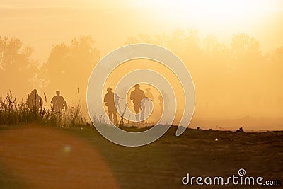 Silhouette action soldiers walking hold weapons the background is smoke and sunset and white balance ship effect dark Editorial Stock Photo