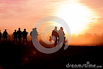 Silhouette action soldiers walking hold weapons the background is smoke and sunset and white balance ship effect dark Editorial Stock Photo