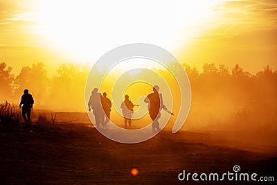 Silhouette action soldiers walking hold weapons the background is smoke and sunset and white balance ship effect dark Editorial Stock Photo