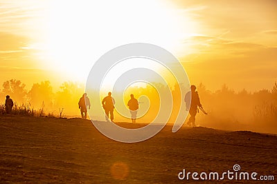 Silhouette action soldiers walking hold weapons the background is smoke and sunset and white balance ship effect dark Editorial Stock Photo