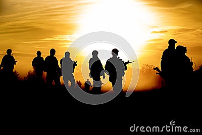 Silhouette action soldiers walking hold weapons the background is smoke and sunset and white balance ship effect dark Stock Photo