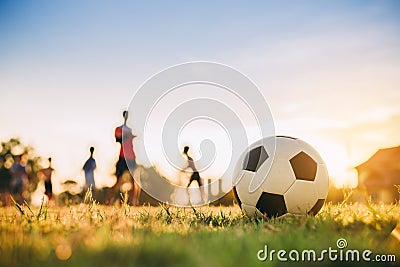 Silhouette action sport outdoors of diversity of kids having fun playing soccer football for exercise in community rural area unde Stock Photo