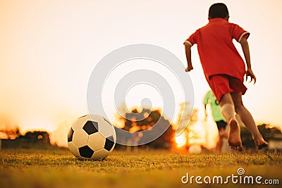 Silhouette action sport outdoors of diversity of kids having fun playing soccer football for exercise in community rural area unde Stock Photo