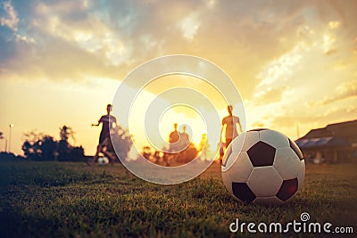 Silhouette action sport outdoors of a group of kids having fun playing soccer football for exercise in community rural area under Stock Photo