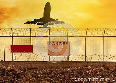 Silhouette airplane flying take off from runway with security razor barbed wire metal fence background Stock Photo