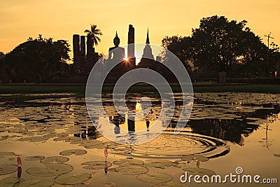 Silhouette of ancient Buddha statue and pagodas against sunset sky at Sukhothai, Thailand. Stock Photo