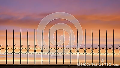 Silhouette arrow spiky metal fence against beautiful sunset sky background Stock Photo