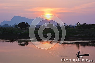 Silhouette of asian fisherman floating in the boat at the sunset Stock Photo