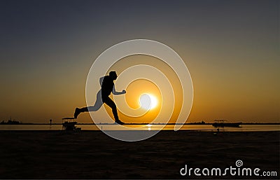 Silhouette of athletic running on the sunrise beach Stock Photo