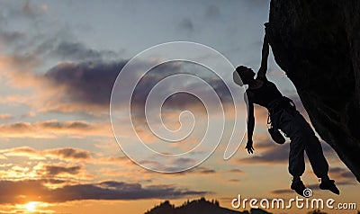 Silhouette of athletic woman climbing steep rock wall Stock Photo