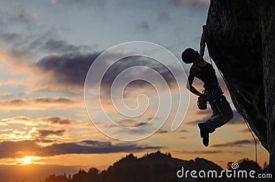 Silhouette of athletic woman climbing steep rock wall Stock Photo