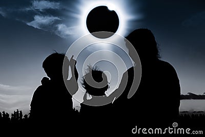 Silhouette back view of family looking at solar eclipse on dark Stock Photo
