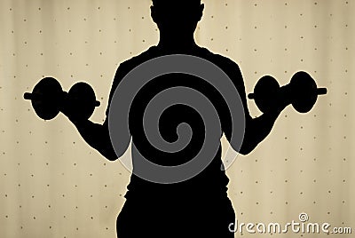 Silhouette of a back young man making a biceps dumbbell curl with yellow curtains at background. Stock Photo