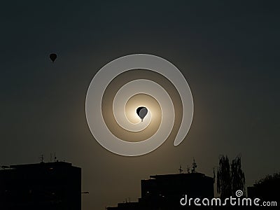 A silhouette of a balloon in the middle of sun with silhouettes of suburb, Balloon Day Hradec Kralove Stock Photo