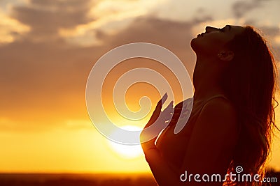 Silhouette of a beautiful girl at sunset in a field, face profile of young woman Stock Photo