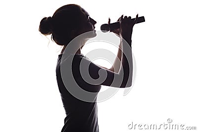 Silhouette of beautiful girl with hand-picked hair singing into microphone, profile of young woman face performing lyric song on Stock Photo