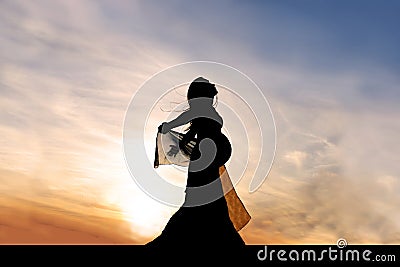 Silhouette of Beautiful Pregnant Woman Outside at Sunset Praising God Stock Photo