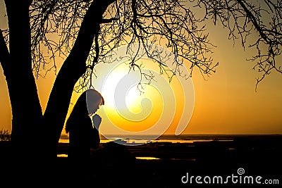 Silhouette of woman praying to God in the nature witth the Bible at sunset, the concept of religion and spirituality Stock Photo