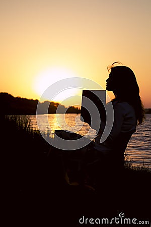 Silhouette of a beautiful young woman reflect on the information read in a book on nature Stock Photo