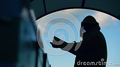 Silhouette of Beekeeper man cleaning wooden frame before harvesting honey in apiary Stock Photo