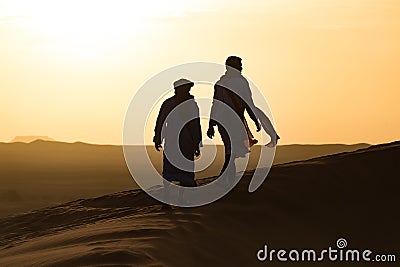 Silhouette of Berber and camel at bloody red sunset, Merzouga in Morocco, Sahara Desert, North Africa Editorial Stock Photo