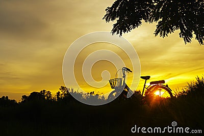 Silhouette of Bicycle and beautiful landscape.Bike at sunset on grass field meadow Stock Photo
