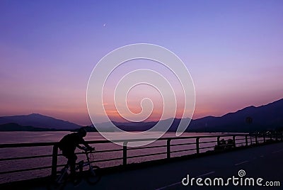 Silhouette of bicycle, fence, mountain, gradient purple sky Stock Photo