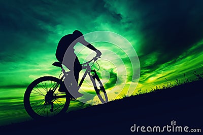 Silhouette of bicyclist against colorful sky at sundown Stock Photo