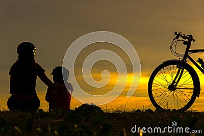 Silhouette biker lovely family at sunset over the ocean. Mom and daughter bicycling at the beach. Stock Photo
