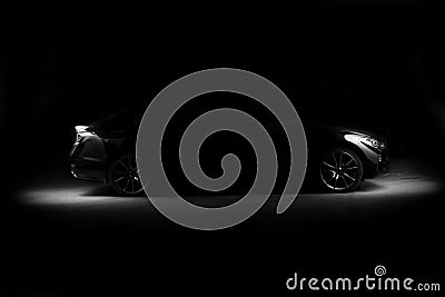 Silhouette of black sports car with headlights on black background Stock Photo