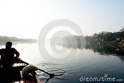 silhouette of boatsman rowing out into the yamuna ganga river in the morning Stock Photo