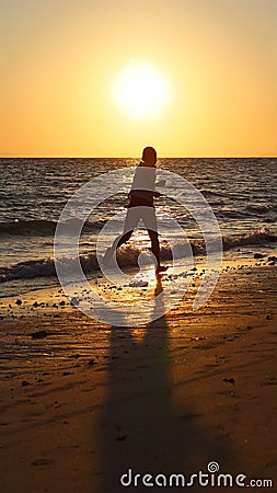 The silhouette of a boy running on the beach Stock Photo