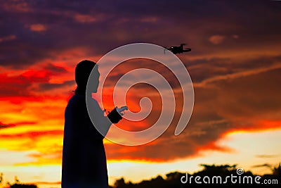 Silhouette of a boys piloting a drone on A Rural Setting on sunset Stock Photo